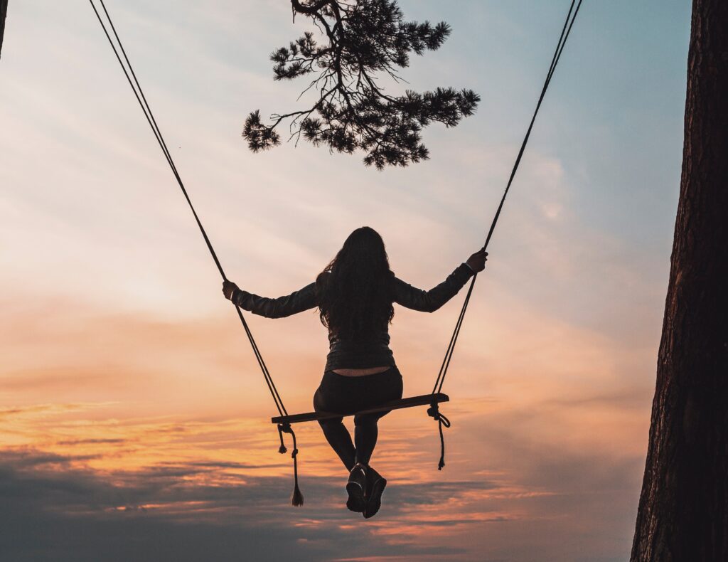 Girl on swing starring at the sunset